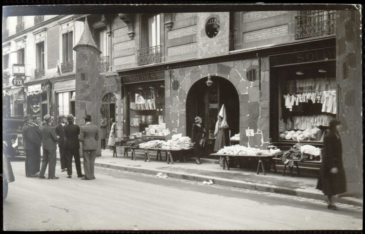 (sans titre), Boulogne-Billancourt . - Braderie commercialeScène de rue lors de la Braderie Commerciale. Au premier plan, devanture d'un commerce ayant une décoration de type médiéval. Au second plan, à droite, présence d'André Morizet et du commerce "Bijoux Fix".