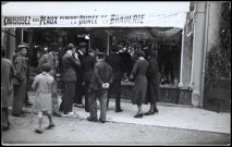 (sans titre), Boulogne-Billancourt . - Braderie commercialeScène de rue lors de la Braderie Commerciale. Devanture d'un commerce avec une banderole ayant pour slogan "Choisissez vos peaux pendant la durée de la Braderie". Au centre, présence d'André Morizet.