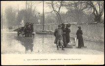 3 - Boulogne inondé - Janvier 1910 - rue de Buzenval, Boulogne-Billancourt. rue Anna Jacquin . - Crue de la Seine, janvier 1910Perspective sur la rue Anna Jacquin, inondée par la crue de la Seine.Au premier plan, 2 dames chapeautées et une autre de moins bonne fortune. 1 sergent de ville les accompagne. Au second plan, une hippomobile.