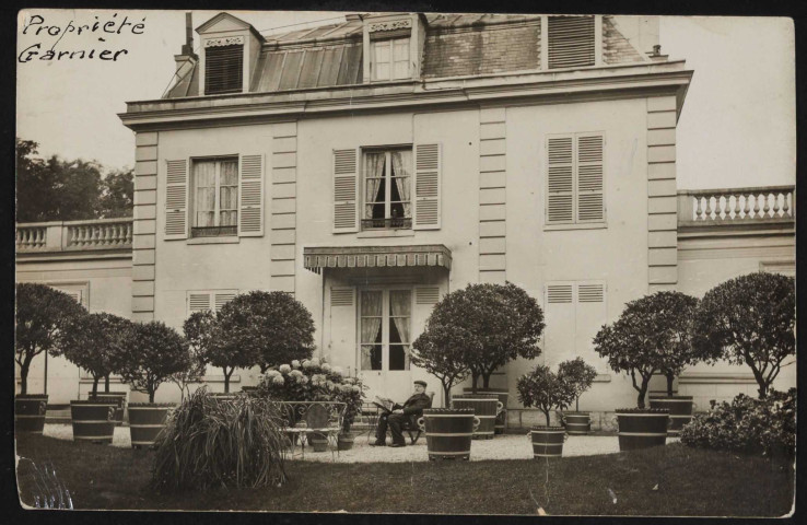 s.t, Boulogne-Billancourt . rue de Sèvres . - propriété de Mr Garnier, façade et jardinPropriété de Mr Garnier au 16 rue de Sèvres. Au premier plan, un monsieur est assons sur une chaise du salon de jardin devant au second plan la façade intérieure.