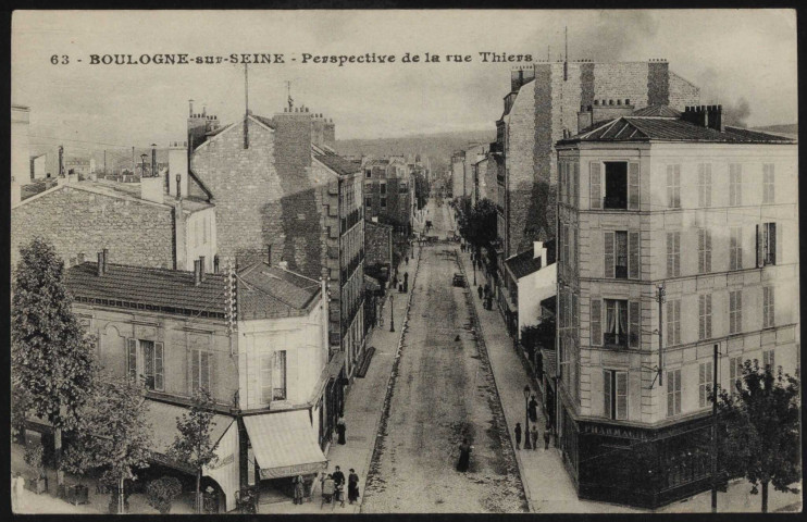 63 - Boulogne-sur-Seine - Rue Thiers, prise de l'Avenue de la Reine, Boulogne-Billancourt . route de la Reine, rue Thiers . - Vue plongeanteAu premier plan la route de la Reine. Au second plan à gauche, un café, au centre la rue Thiers, à droite une pharmacie